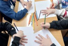 Dzieci odrysowują na kartkach papieru swoją dłoń