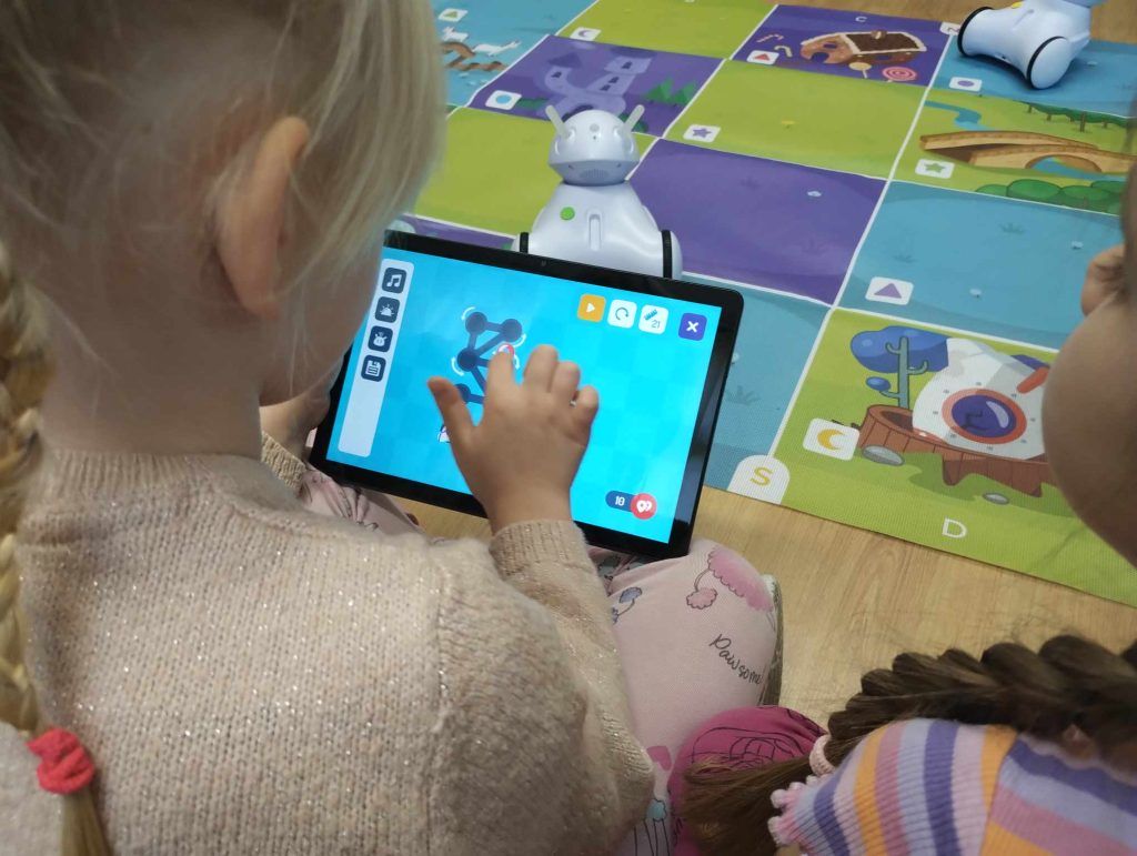 Dziewczynka rysuje na ekranie tabletu drogę dla robota.
