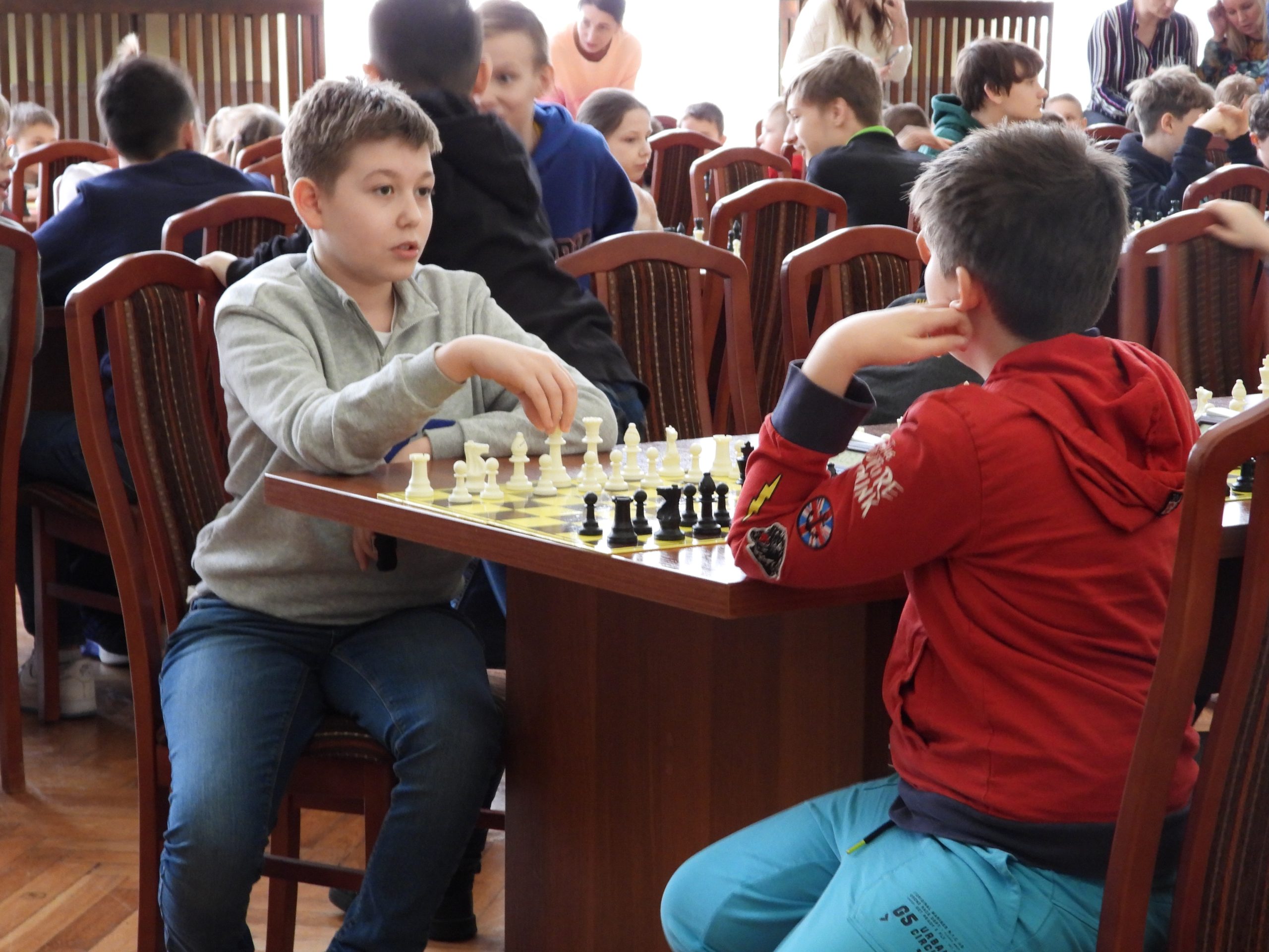 Chłopcy siedzą przy szachownicy.